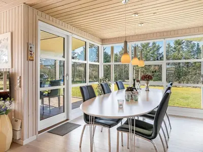 a dining room with a table and chairs and windows at Holiday Home Troels - 750m from the sea by Interhome in Løkken