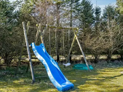 a playground with a blue slide in the grass at Holiday Home Troels - 750m from the sea by Interhome in Løkken