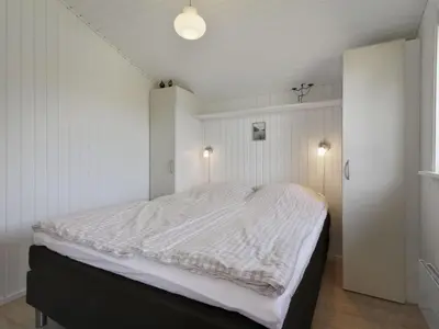 a bedroom with a large bed with white sheets at Holiday Home Eden - 800m from the sea by Interhome in Løkken