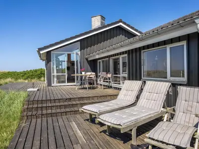 two chairs and a table on a wooden deck at Holiday Home Lauri - 350m from the sea by Interhome in Løkken