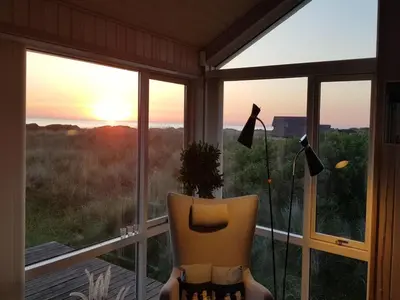 a chair sitting in front of a window with the sunset at Holiday Home Lauri - 350m from the sea by Interhome in Løkken