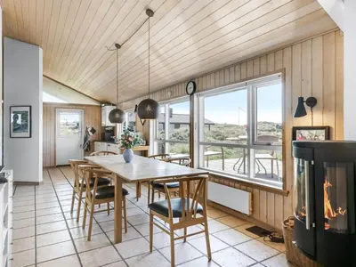 a dining room with a table and chairs and a fireplace at Holiday Home Lauri - 350m from the sea by Interhome in Løkken