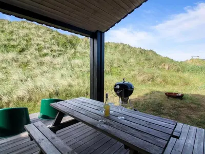 a wooden picnic table with wine glasses on a porch at Holiday Home Mikkel - 300m from the sea by Interhome in Løkken