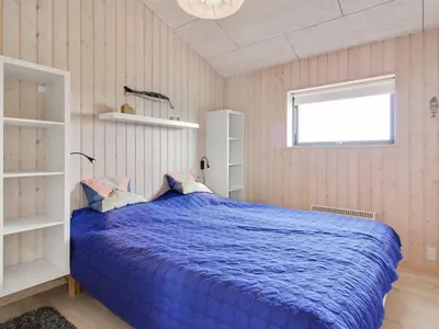 a bedroom with a blue bed and a window at Holiday Home Mikkel - 300m from the sea by Interhome in Løkken