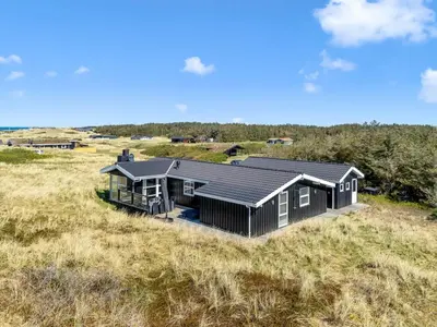 a black house in the middle of a field at Holiday Home Ingela - 350m from the sea by Interhome in Løkken