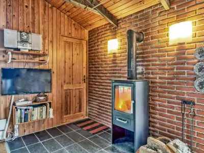 a brick room with a stove and a tv at Holiday Home Conradine - 500m from the sea by Interhome in Løkken