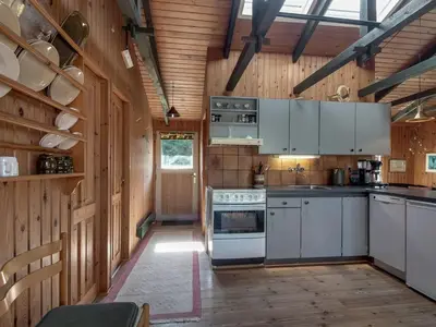 a kitchen with white appliances and wooden walls at Holiday Home Conradine - 500m from the sea by Interhome in Løkken