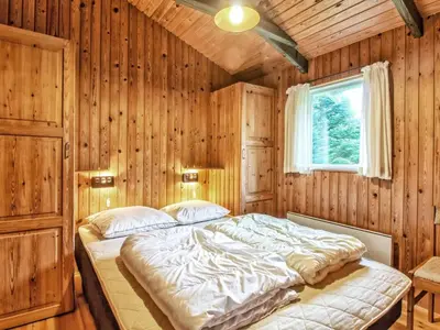 a bedroom with a large bed in a wooden wall at Holiday Home Conradine - 500m from the sea by Interhome in Løkken