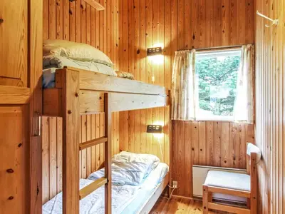a bedroom with a bunk bed in a wooden cabin at Holiday Home Conradine - 500m from the sea by Interhome in Løkken