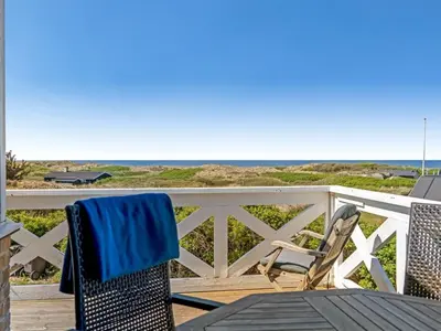 a table and chairs on a deck with the beach at Holiday Home Mielikki - 200m from the sea by Interhome in Løkken