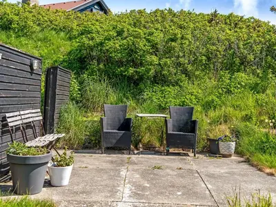 a patio with two chairs and a table and plants at Holiday Home Mielikki - 200m from the sea by Interhome in Løkken
