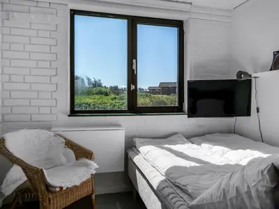 a bedroom with a bed and a tv and a chair at Holiday Home Mielikki - 200m from the sea by Interhome in Løkken