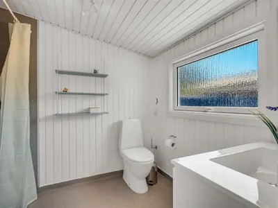 a bathroom with a toilet and a sink and a window at Holiday Home Tonja - 300m from the sea by Interhome in Løkken