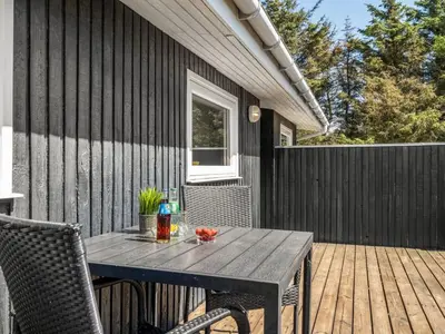 a wooden table sitting on a wooden deck with a table at Holiday Home Tonja - 300m from the sea by Interhome in Løkken