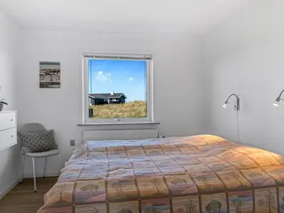 a bedroom with a bed and a window with a house at Holiday Home Nayeli - 275m from the sea by Interhome in Løkken