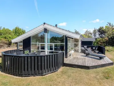 a house with a large deck with two chairs at Holiday Home Elvan - 450m from the sea by Interhome in Løkken