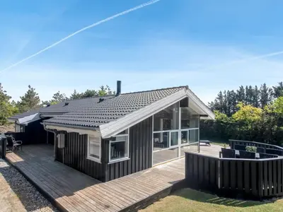 a house with a wooden deck with a roof at Holiday Home Elvan - 450m from the sea by Interhome in Løkken