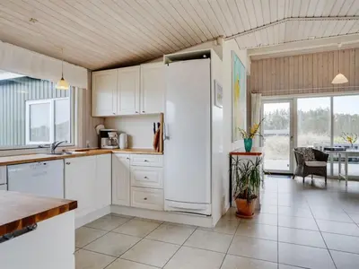 a kitchen with a white refrigerator and a table at Holiday Home Elco - 450m from the sea by Interhome in Løkken