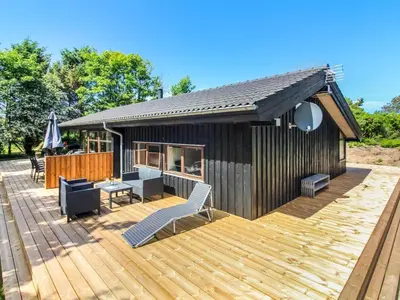 a wooden deck with chairs and a house at Holiday Home Paulette - 450m from the sea by Interhome in Løkken