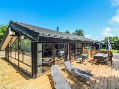 a house with a deck with chairs and a grill at Holiday Home Paulette - 450m from the sea by Interhome in Løkken