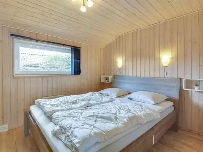a bedroom with a large bed in a wooden wall at Holiday Home Susan - 600m from the sea by Interhome in Løkken