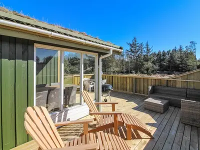 a deck with two chairs and a bench on it at Holiday Home Taina - 1-1km from the sea by Interhome in Løkken