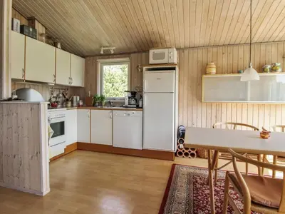 a kitchen with white cabinets and a table in it at Holiday Home Taina - 1-1km from the sea by Interhome in Løkken