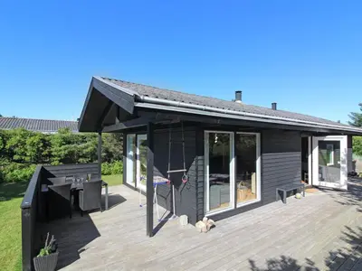 a black house with a large wooden deck at Holiday Home Eyer - 800m from the sea by Interhome in Løkken