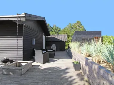 a patio with a table and chairs and a fence at Holiday Home Eyer - 800m from the sea by Interhome in Løkken