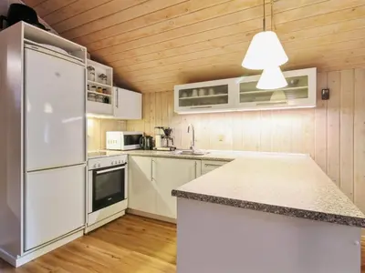 a kitchen with white appliances and a wooden ceiling at Holiday Home Elsemaria - 1-3km from the sea by Interhome in Løkken