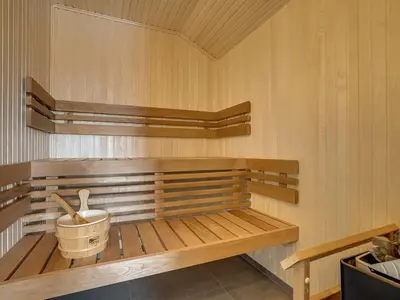 a sauna with a wooden bench and a bucket at Holiday Home Fegge - 1-5km from the sea by Interhome in Løkken