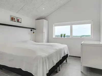 a white bedroom with a large bed and a window at Holiday Home Fegge - 1-5km from the sea by Interhome in Løkken