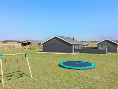 a playground with a trampoline and a swing at Holiday Home Eveline - 1-5km from the sea by Interhome in Løkken