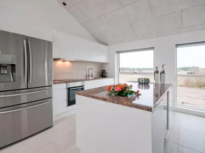 a kitchen with white cabinets and stainless steel appliances at Holiday Home Eveline - 1-5km from the sea by Interhome in Løkken