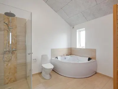 a bathroom with a white tub and a toilet at Holiday Home Eveline - 1-5km from the sea by Interhome in Løkken