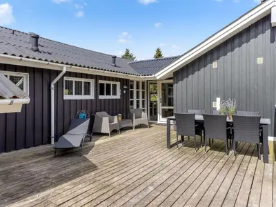 a deck with chairs and a table on a house at Holiday Home Lempi - 300m from the sea by Interhome in Løkken