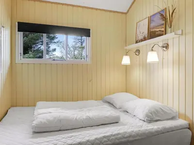 a bedroom with a bed with white sheets and a window at Holiday Home Lempi - 300m from the sea by Interhome in Løkken