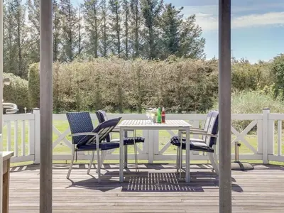 a table and four chairs on a deck with a fence at Holiday Home Sonke - 500m from the sea by Interhome in Løkken
