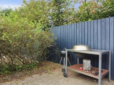 a grill on a cart next to a fence at Holiday Home Sonke - 500m from the sea by Interhome in Løkken