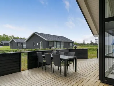 a deck with a table and chairs on a house at Holiday Home Ina - 1-2km from the sea by Interhome in Løkken