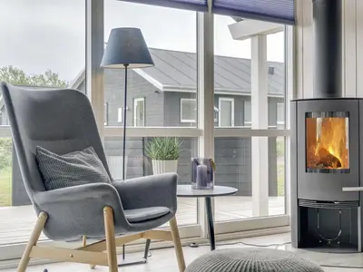 a living room with a chair and a fireplace at Holiday Home Ina - 1-2km from the sea by Interhome in Løkken