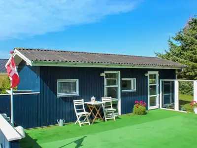 a blue tiny house with a table and chairs at Holiday Home Gitten - 600m from the sea by Interhome in Løkken