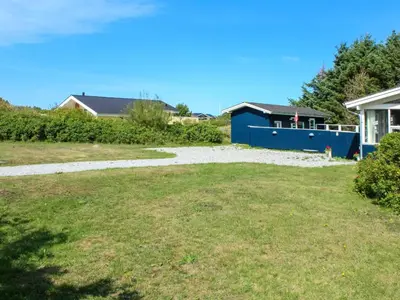 a yard with a blue building and a house at Holiday Home Gitten - 600m from the sea by Interhome in Løkken