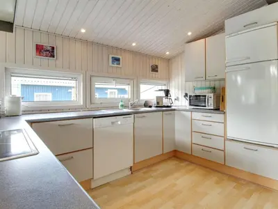a kitchen with white cabinets and a white refrigerator at Holiday Home Gitten - 600m from the sea by Interhome in Løkken