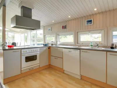 a large kitchen with white appliances and windows at Holiday Home Gitten - 600m from the sea by Interhome in Løkken