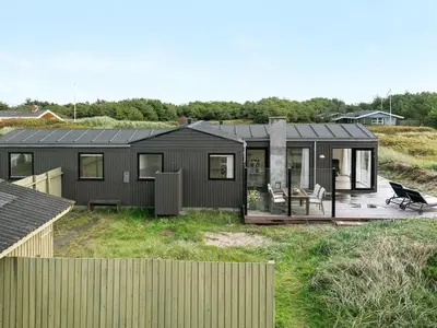 a black house on a hill with a deck at Holiday Home Marino - 480m from the sea by Interhome in Løkken