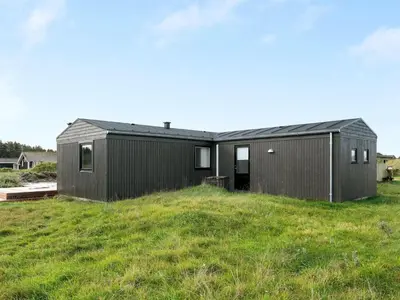 a black house on top of a green field at Holiday Home Marino - 480m from the sea by Interhome in Løkken