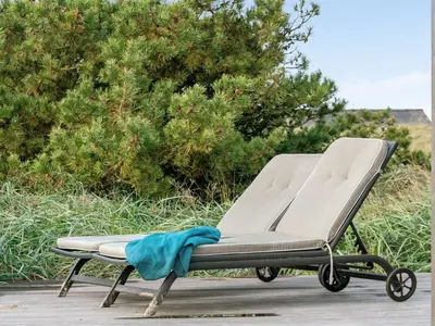 a reclining beach chair with a blue towel on it at Holiday Home Marino - 480m from the sea by Interhome in Løkken