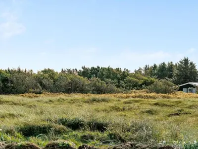 a field of grass with a house in the background at Holiday Home Marino - 480m from the sea by Interhome in Løkken