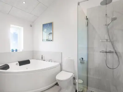 a bathroom with a tub and a toilet and a shower at Holiday Home Dwerg - 1-5km from the sea by Interhome in Løkken